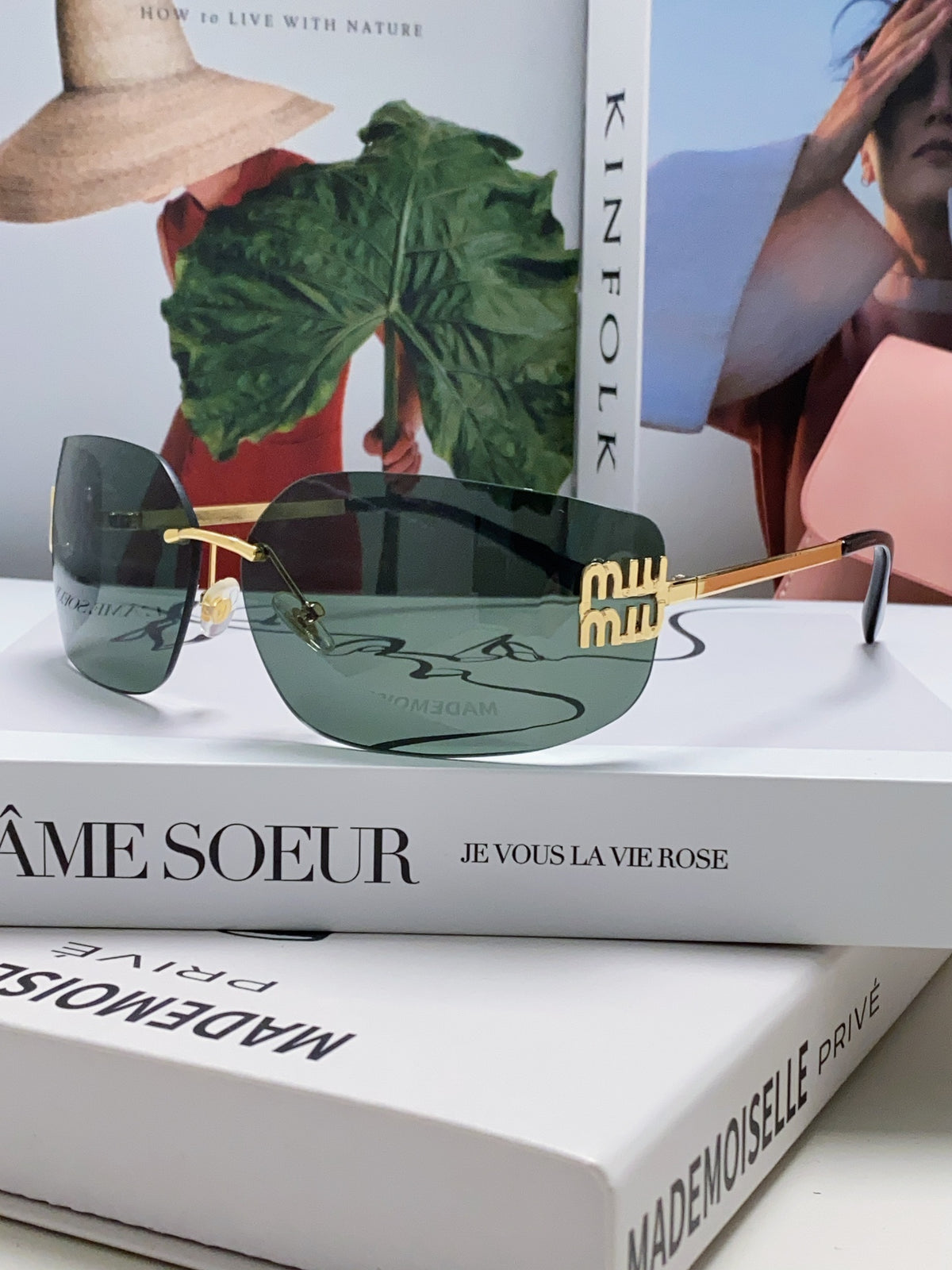Miu miu sunglasses displayed on a stack of fashion magazines with a stylish background.