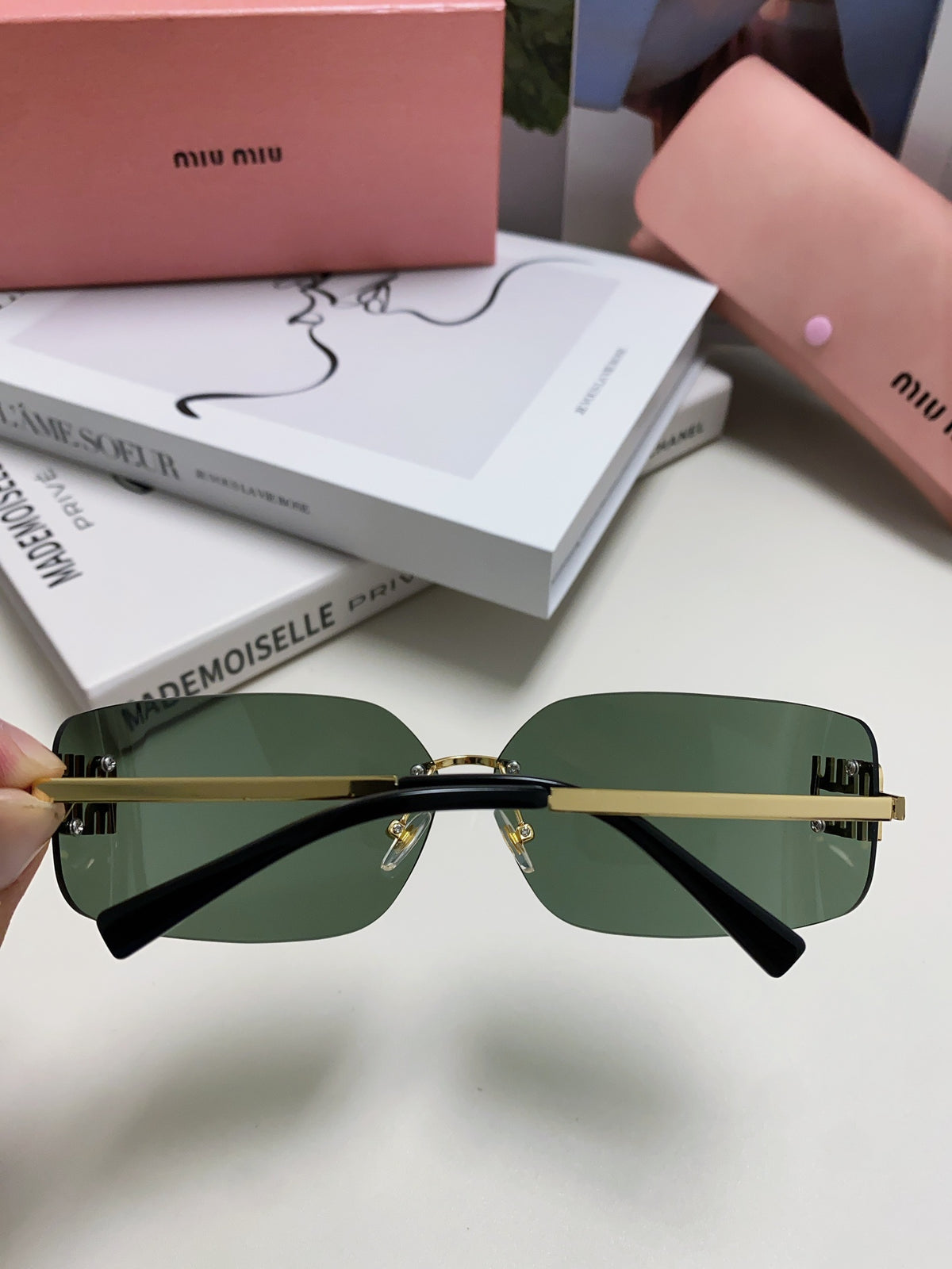 Miu miu sunglasses displayed with green lenses and gold accents against stylish background.